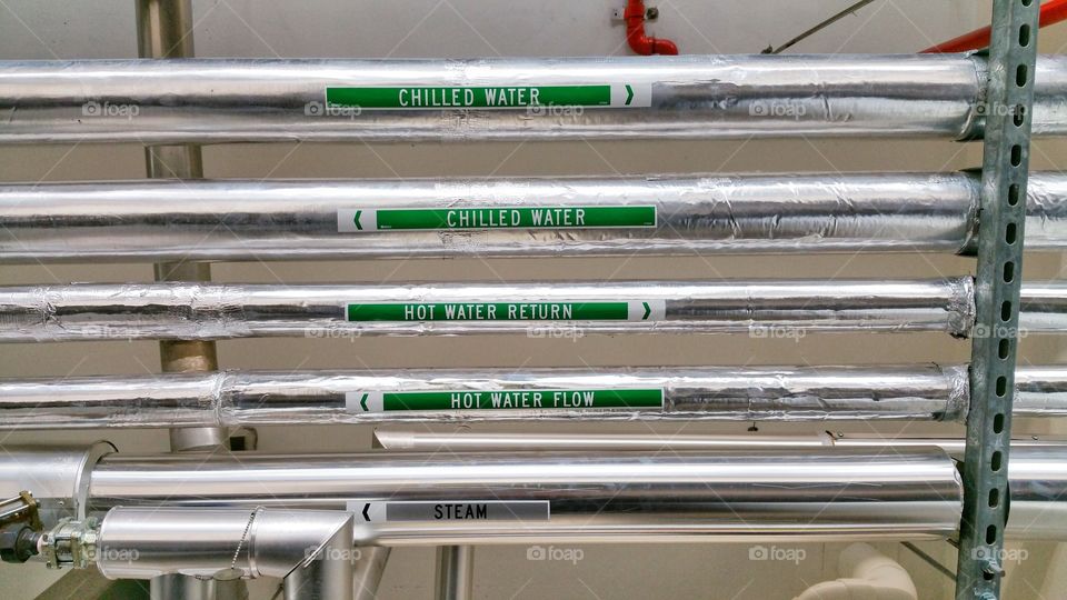 Overhead chilled water, hot water and steam pipes that are clearly labeled for safety and maintenance purposes. These can often be seen in commercial buildings and residential complexes.