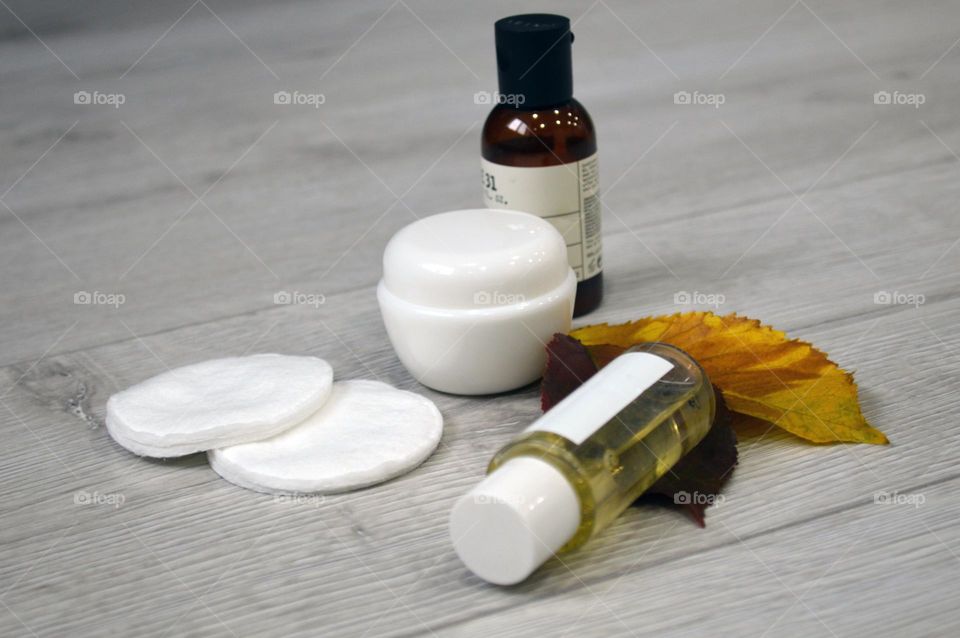 Jars with cream, shampoo and cosmetics on a background with autumn leaves