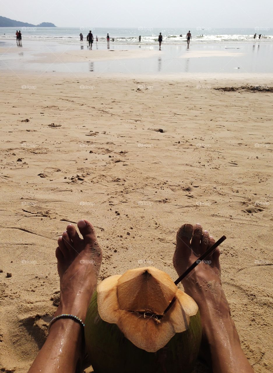 Enjoying reflux with coconut cocktail on sandy beach during lazy summer days 