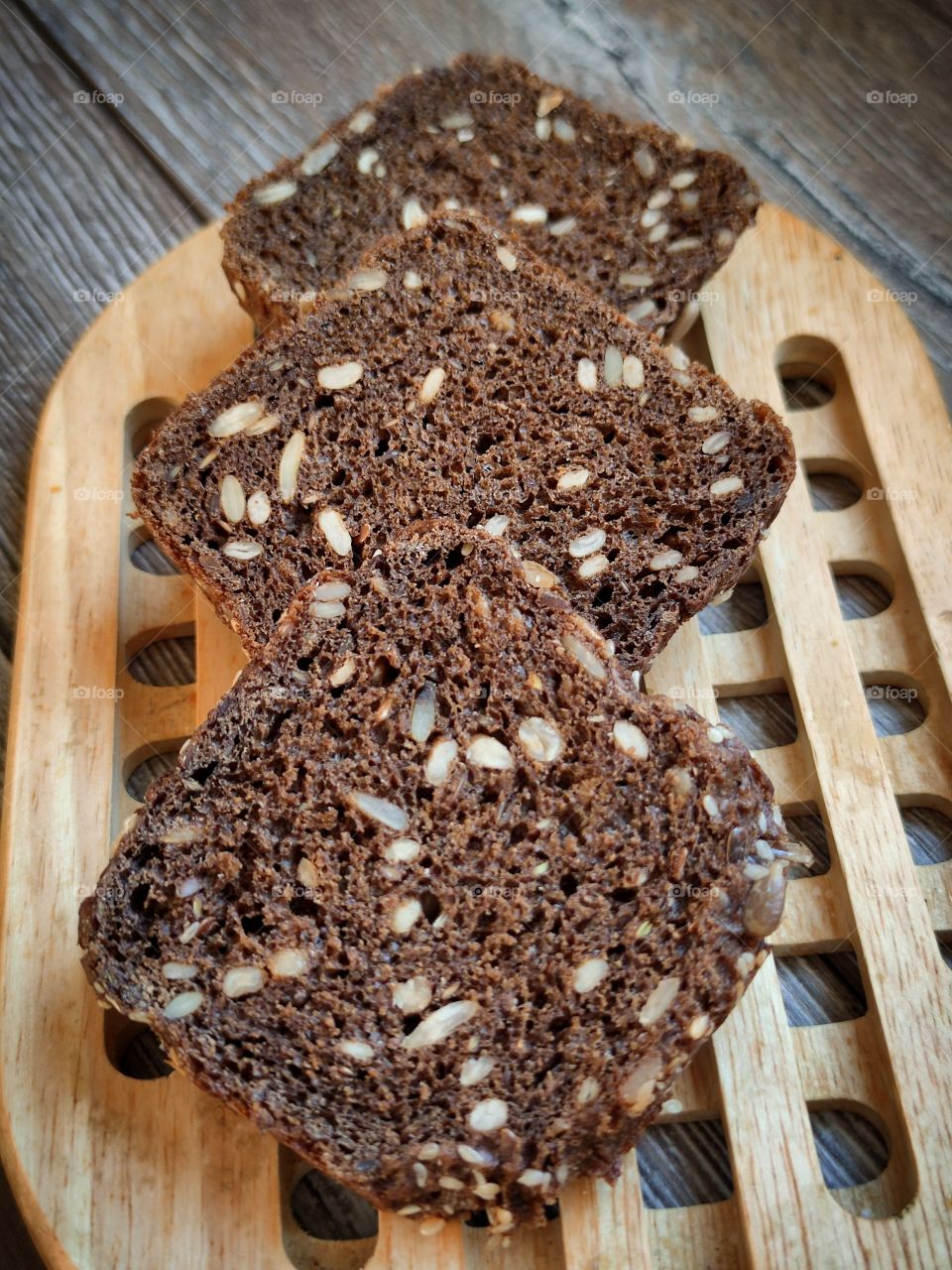 Three pieces of black bread with sunflower seeds on a wooden substrate