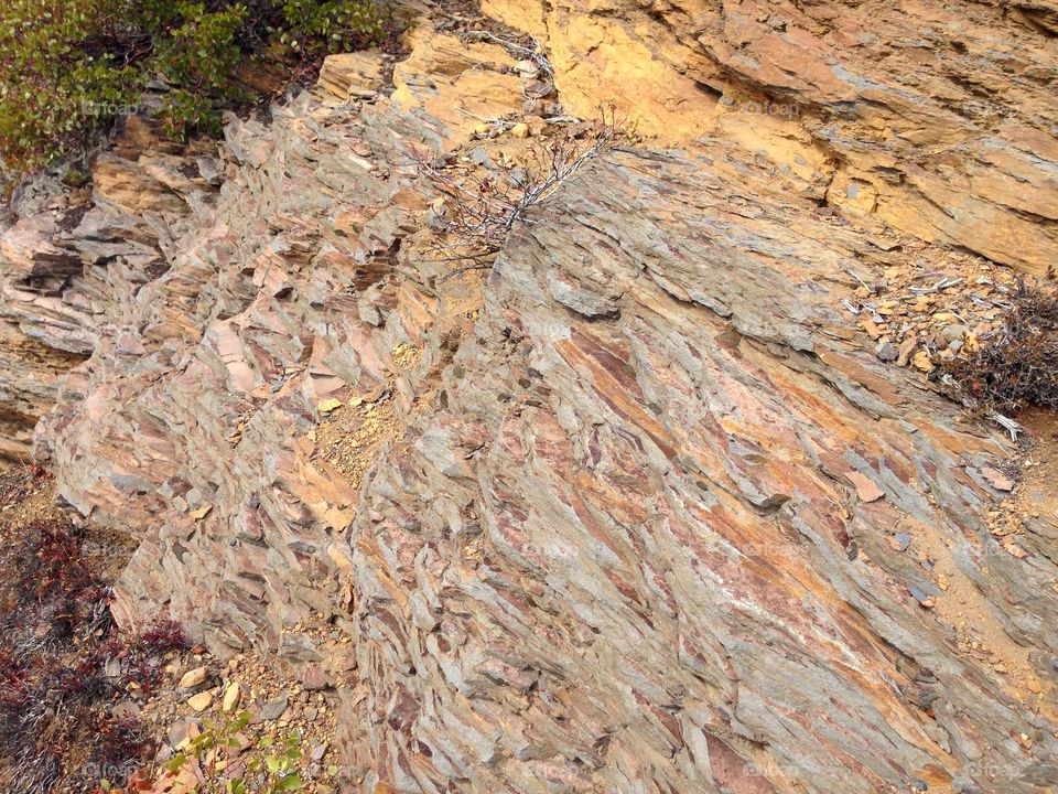 Rough layers of beautiful reddish brown rock on a hillside in Central Oregon on a sunny day. 