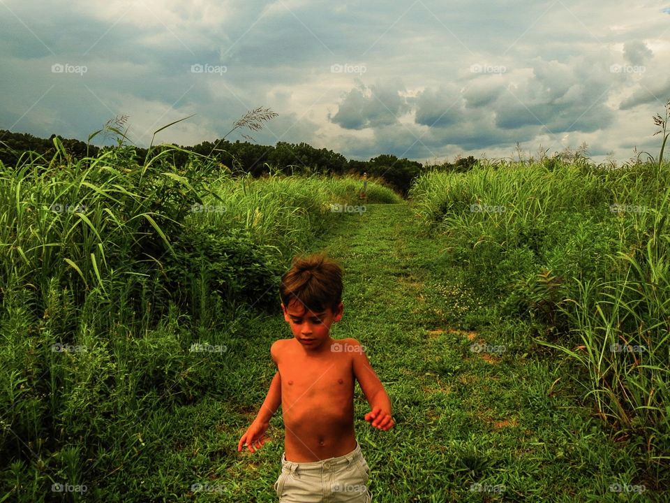 Field of Dreams. Boy running through a field on a freshly mowed path, as we out- run a gathering storm