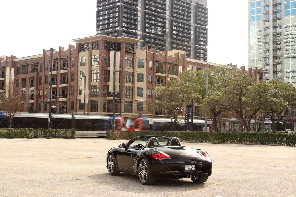 Black porsche convertible in city with moving train, luxury car