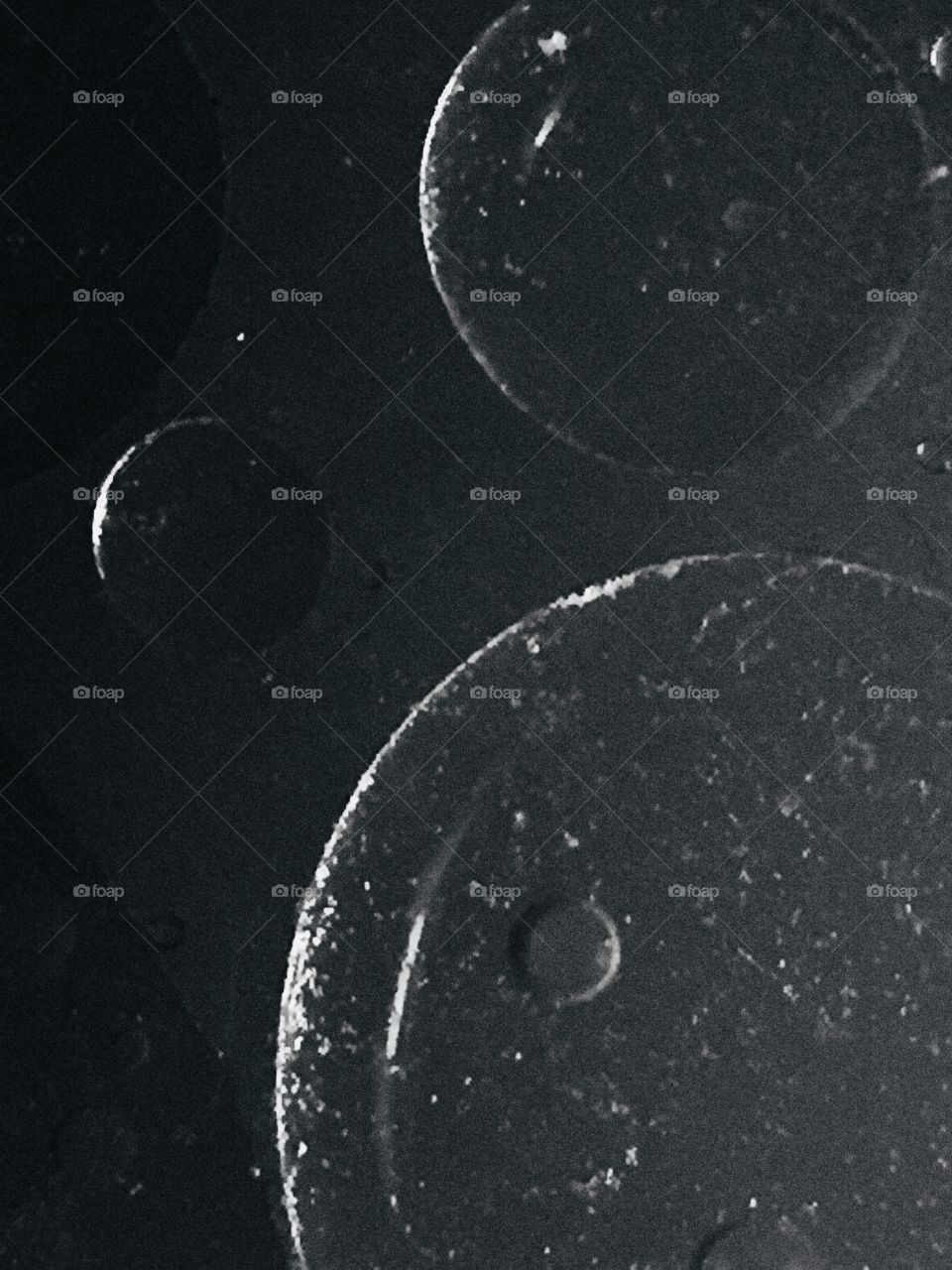 An abstract of different sized circles in black and white. There are circles within circles giving texture. The shadows and highlights make the circles look like silvery planets or moons.