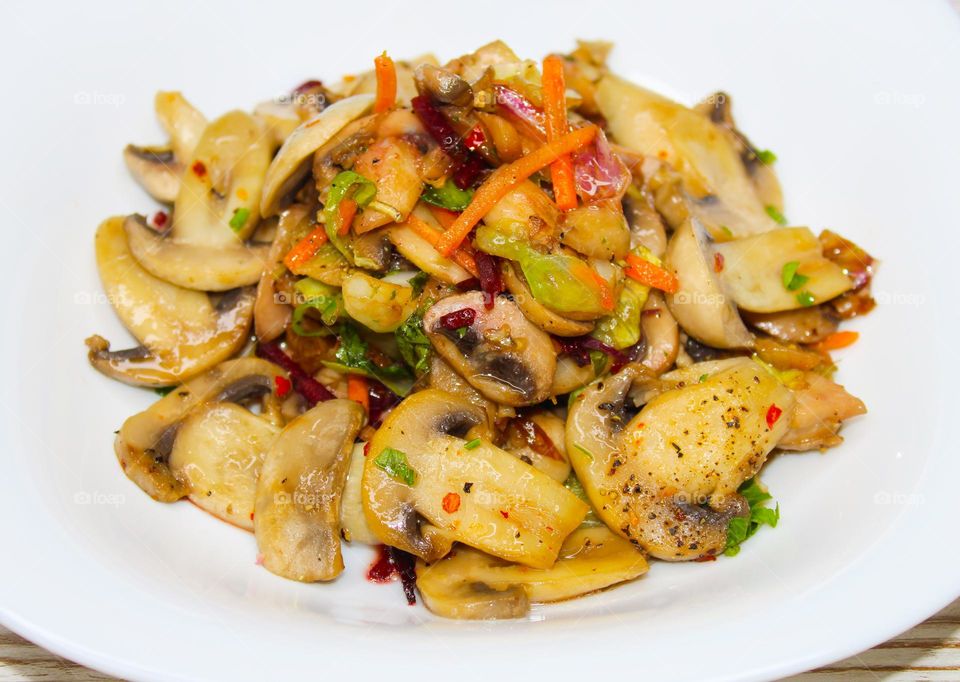 Stewed mushrooms with vegetables on a white plate