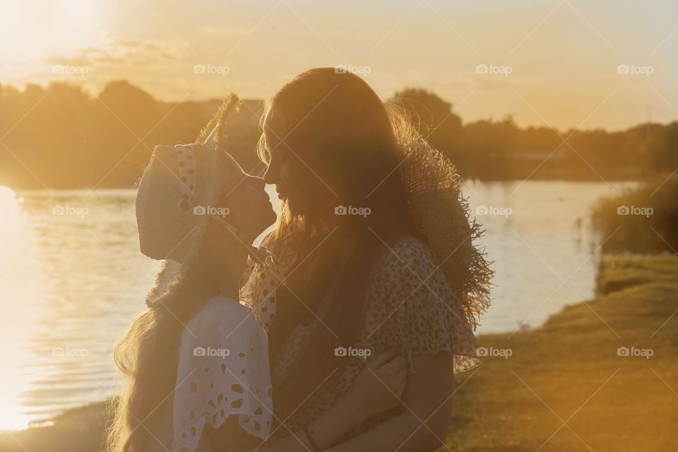 mother and daughter on the background of the setting sun