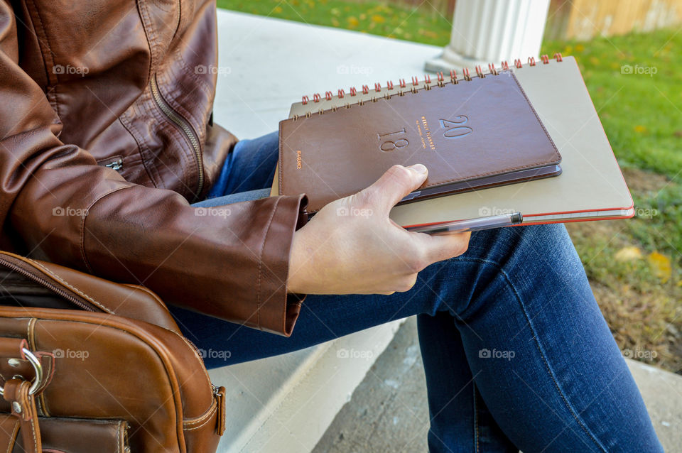 Woman holding At-a-Glance planner and notebook while sitting on concrete steps