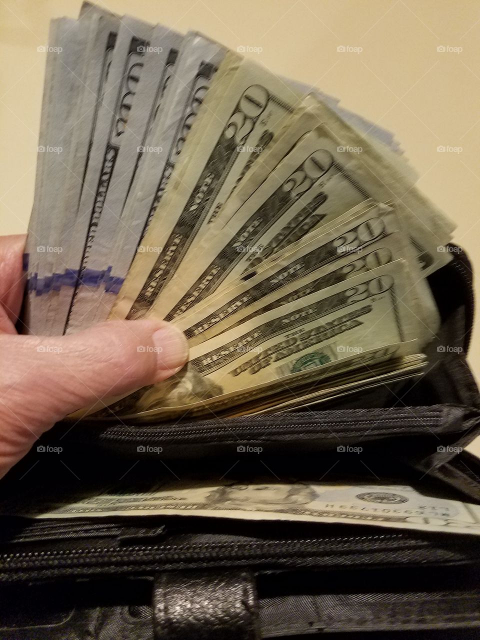 Cash in $20 & $100 dollar bills held in hand.