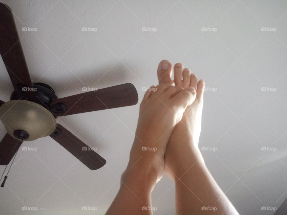 a female rubbing her feet against her legs in a sexy pose while laying in her bedroom.