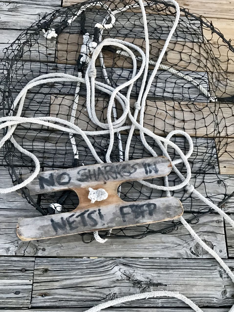 A sign on a fishing net seen while strolling the beach pier