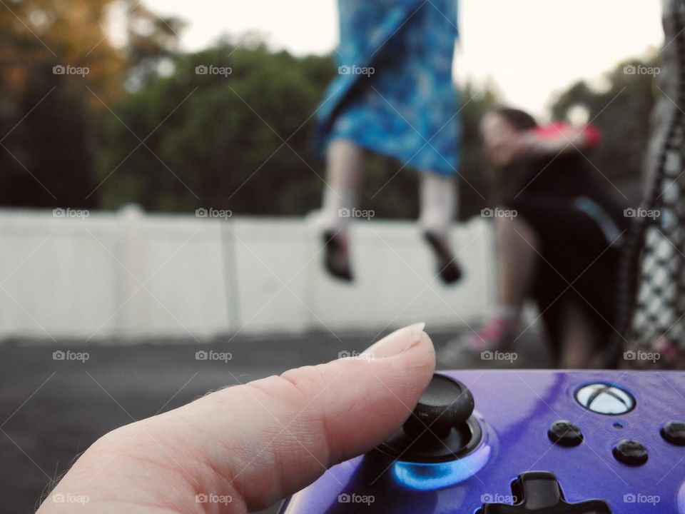 Xbox purple blue colored remote accessory used as if the mother is playing a game called: bring the children on the trampoline and play outside.