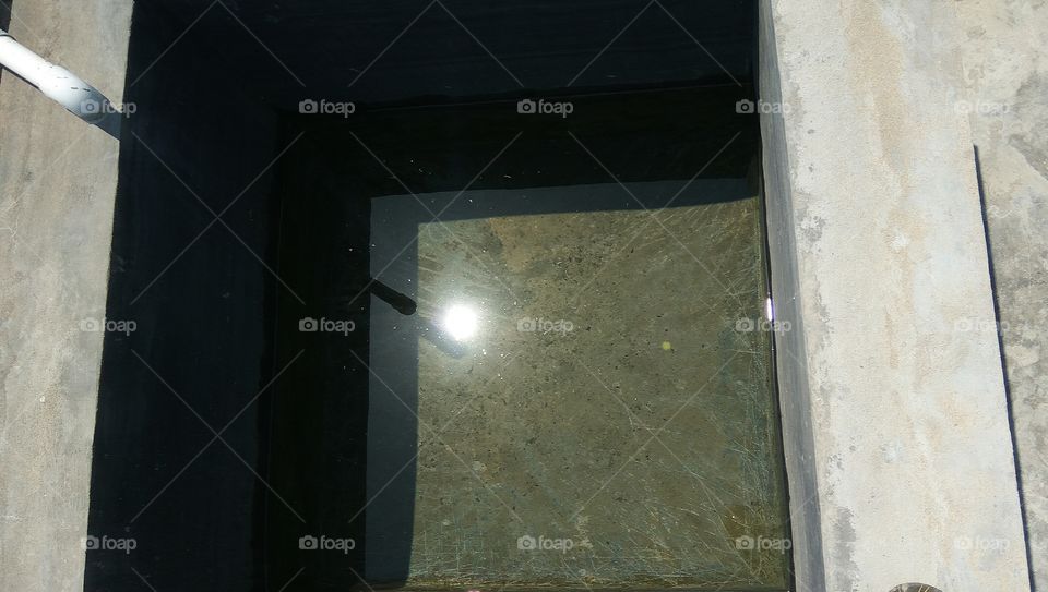 Water tub in sun reflected in water