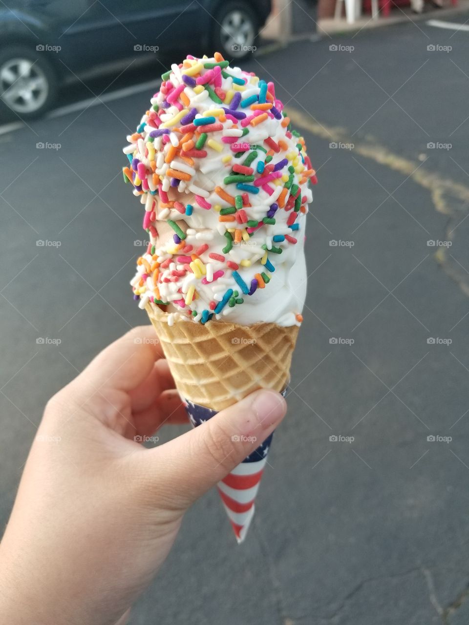 A soft-serve vanilla ice cream cone with rainbow sprinkles.