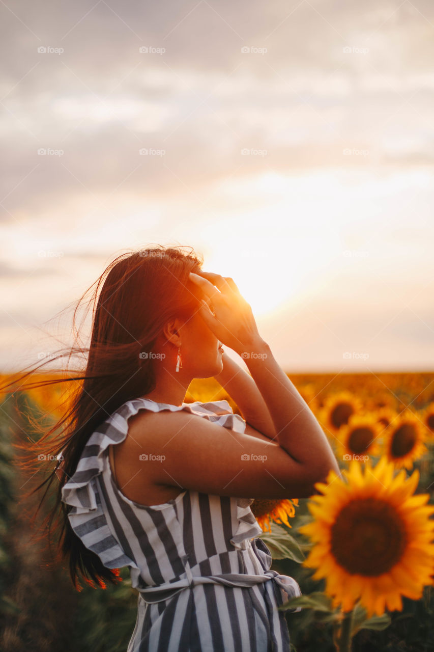 Girl in a sunflower field in sunset