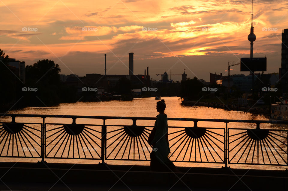 Berlin, sunset view on the Spree from Oberbaumbrücke with silhouette of a woman and the radio tower in the background 