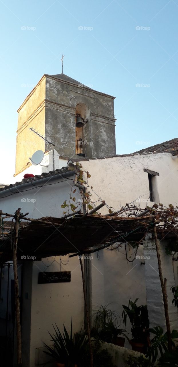 antiquísimo campanario de Iglesia perteneciente al Castillo del Castellar sobresaliendo por encima de las casitas del poblado que lo antecede.