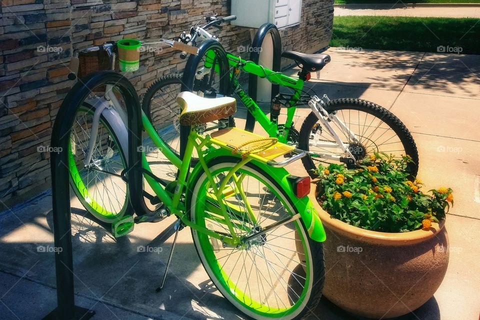 Two green bikes parked in an urban bicycle rack clash of color