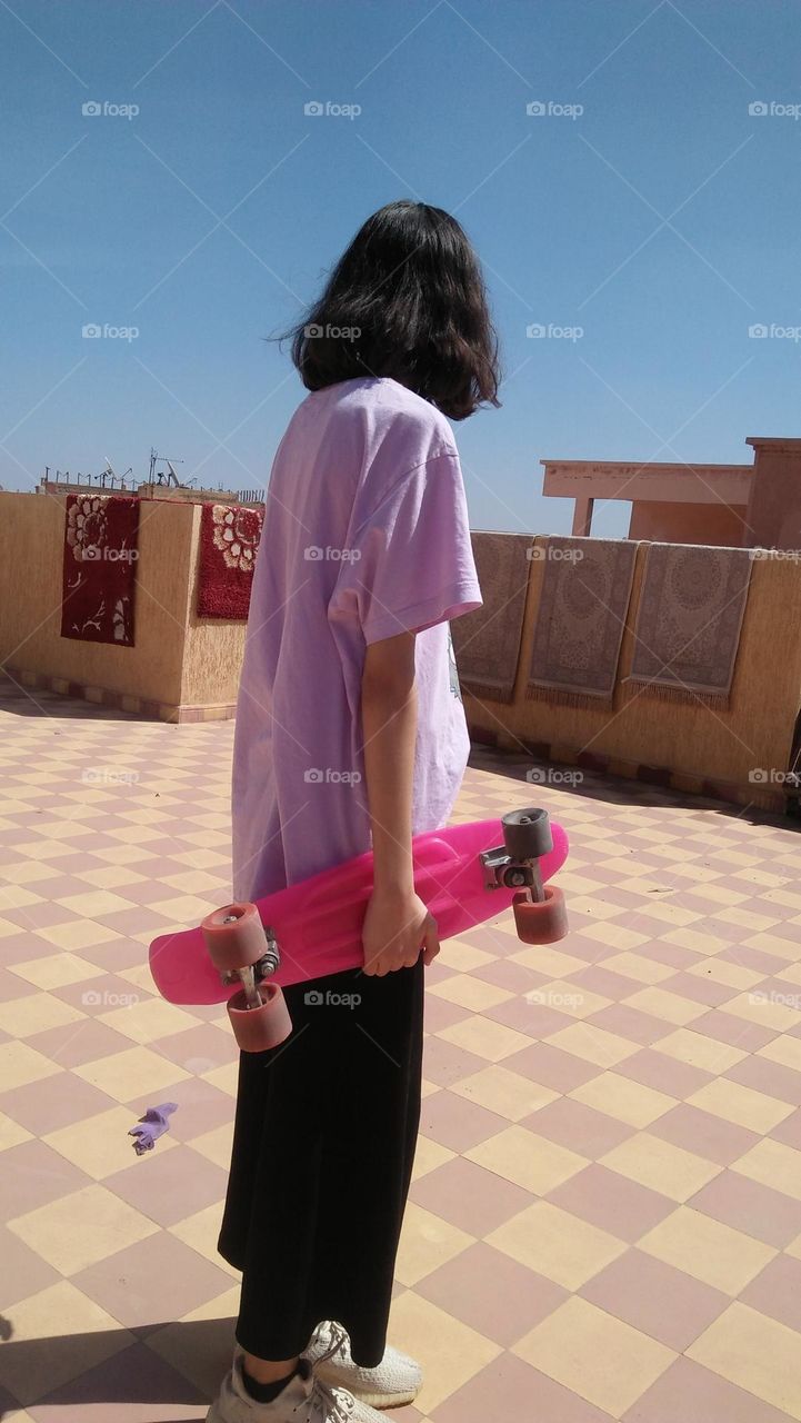 Young girl holding  pink skate board