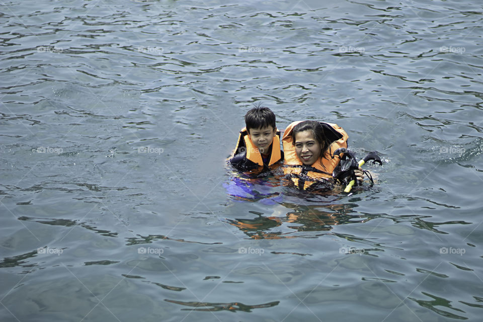 Woman and boy wearing a life jacket, scuba diving in the sea.