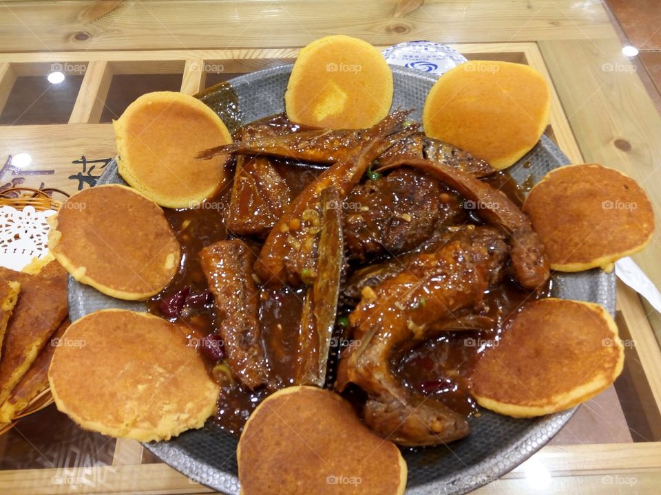 Fried fish in a spicy sauce on metallic dish.