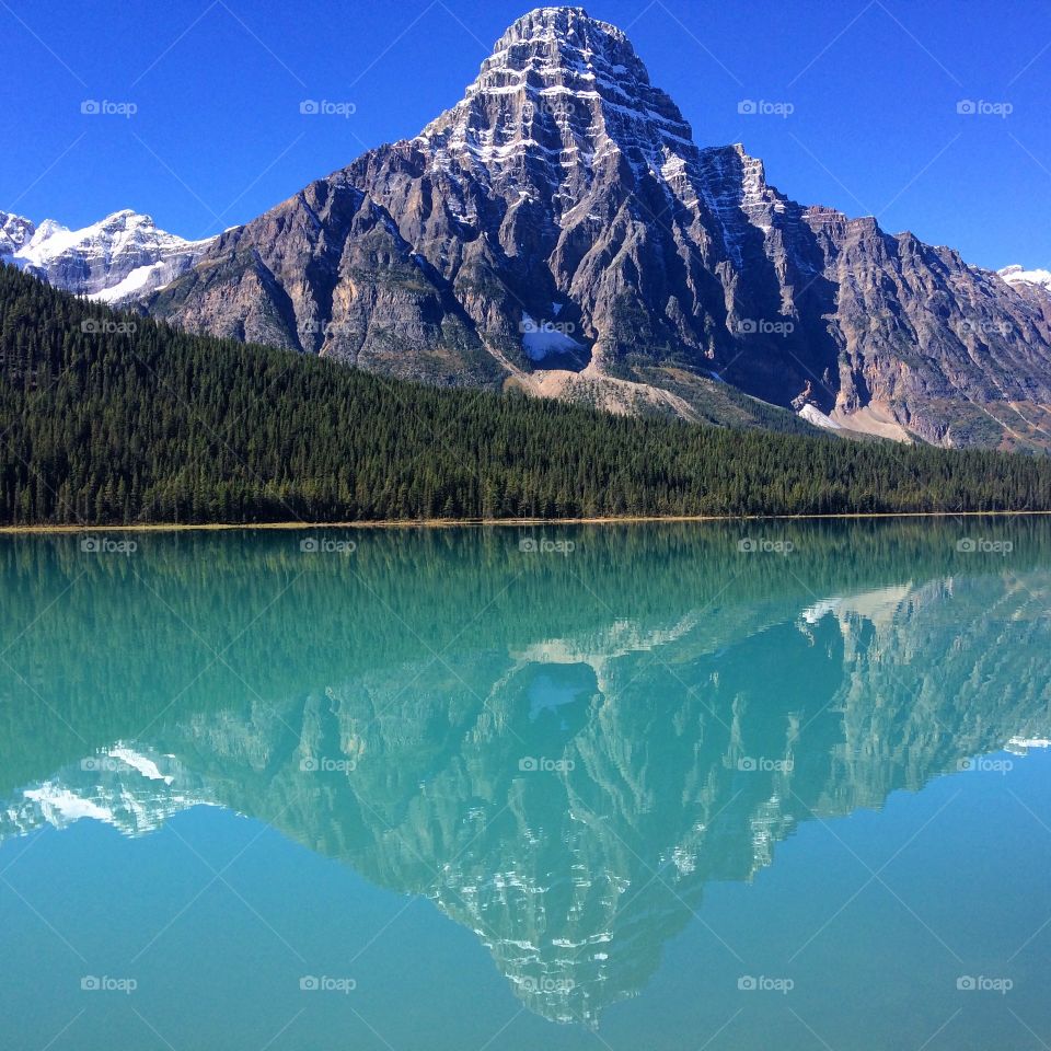 Forest and rocky mountains reflected on lake