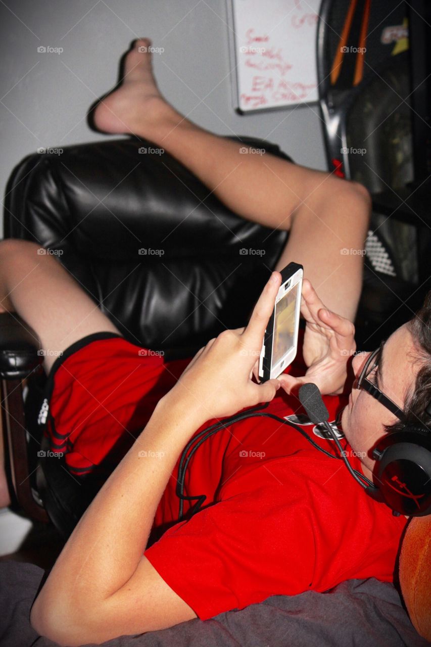 Teen laying half on the bed and half on a chair