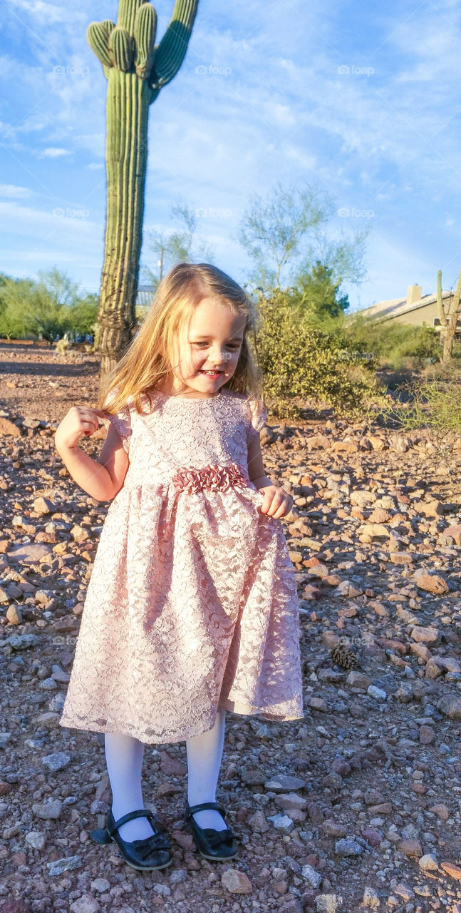 Little girl standing in front of big saguaro cactus