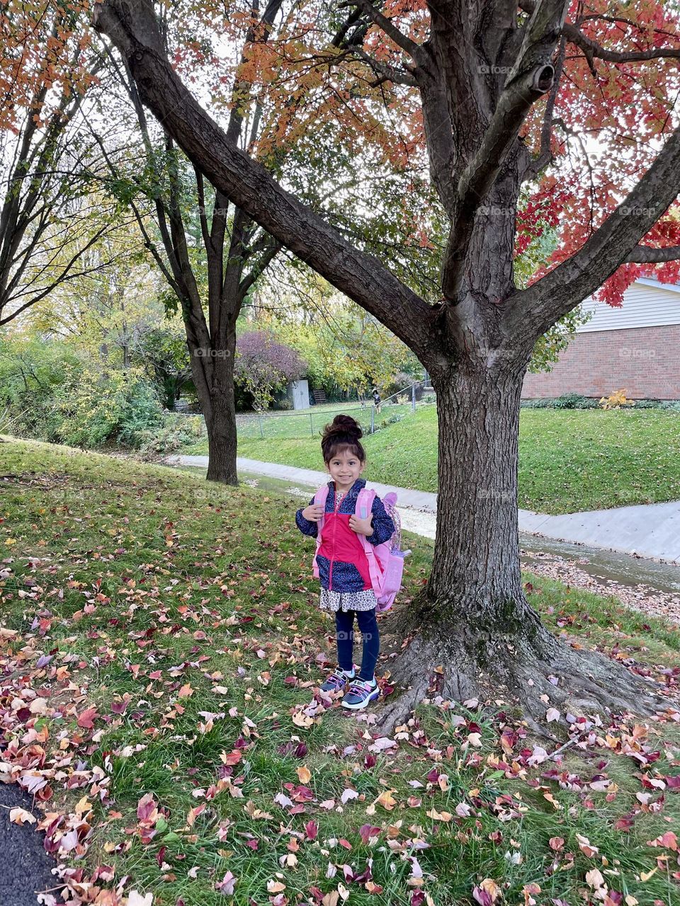 Little girl with backpack on ready for school, starting preschool in the fall time, little girl poses with backpack under tree 