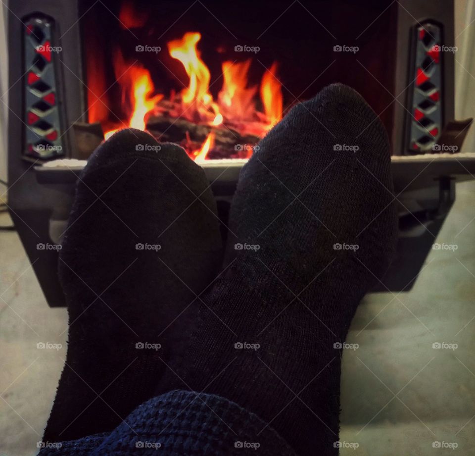 Sock feet in front of a wood burning stove with fire relaxing warm winter inside flame heat cozy fun glow woman