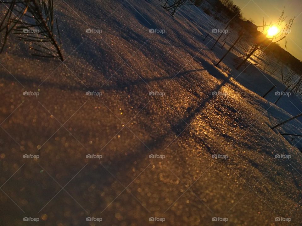 photo of snowy landskape at sunset. Snow reflects sunlight. Photo is in warm photos