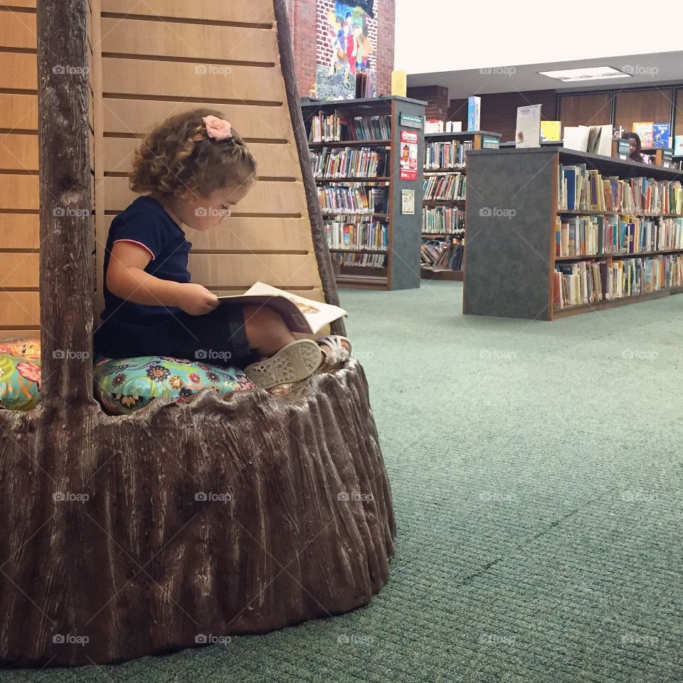 Girl reading book in library