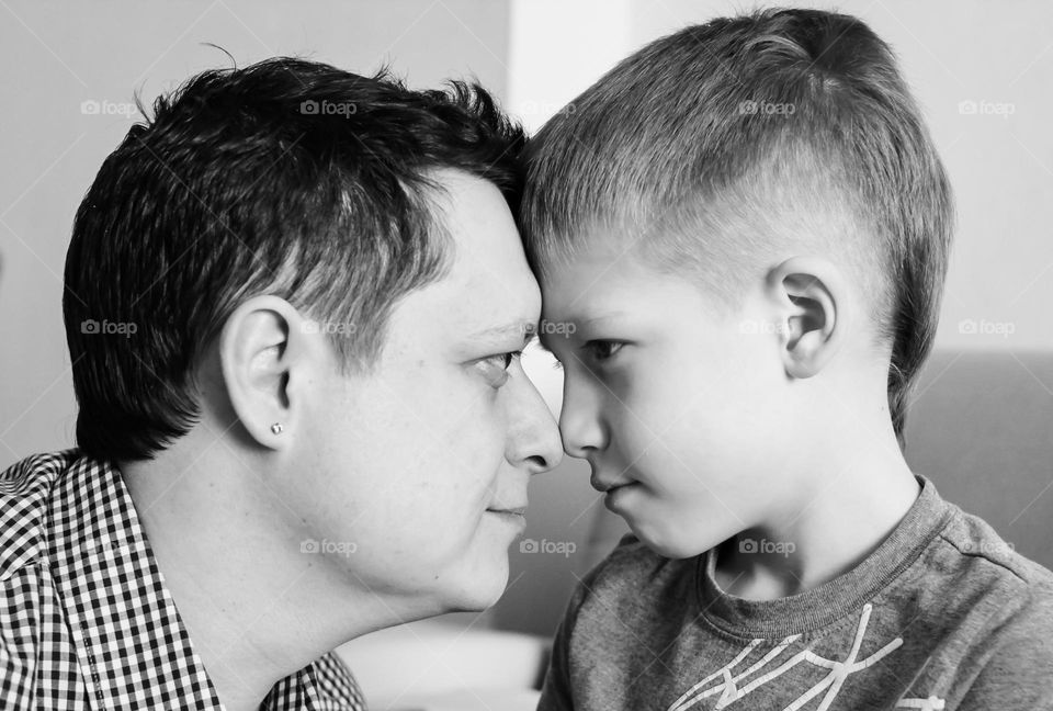 Close-up black and white portrait of father and son looking into each other's eyes