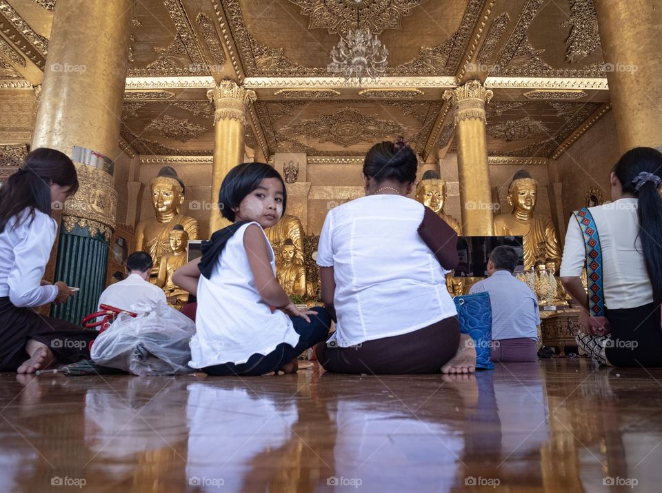 Myanmar grandma and kid  are praying inside building at  Shwedagon pagoda