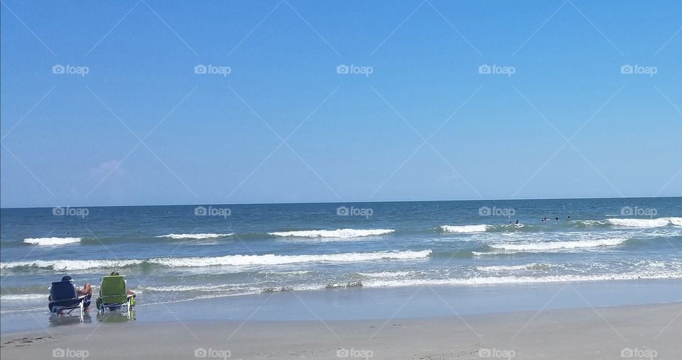 two people, alone, by the big beautiful Ocean.  Huntington beach South Carolina.