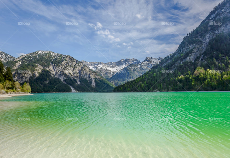 Beautiful landscape of green water lake in Austria with mountains on background in spring 
