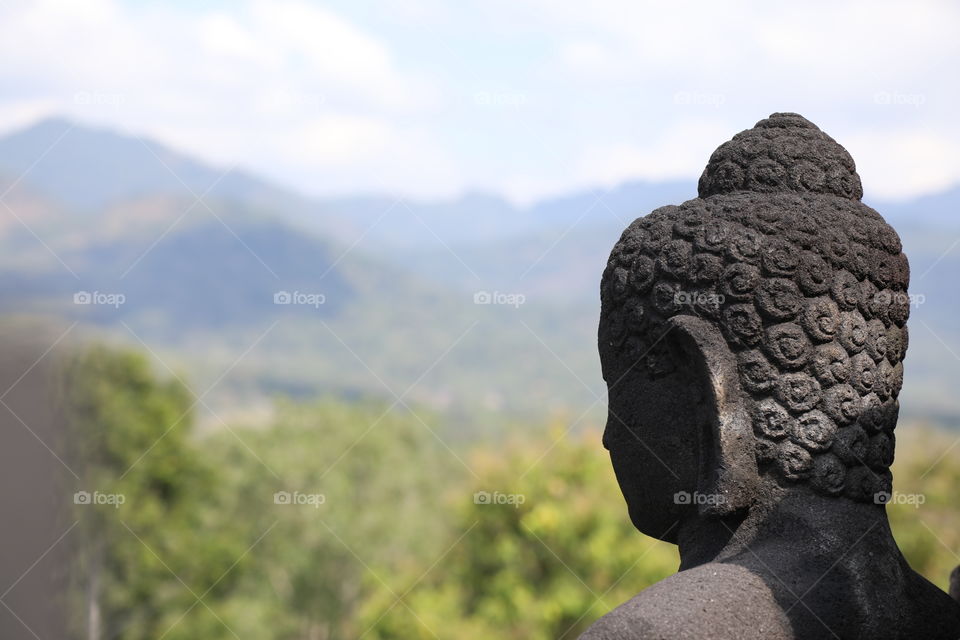 A statue of Buddha looks out over the countryside at Borobudur temple, Indonesia