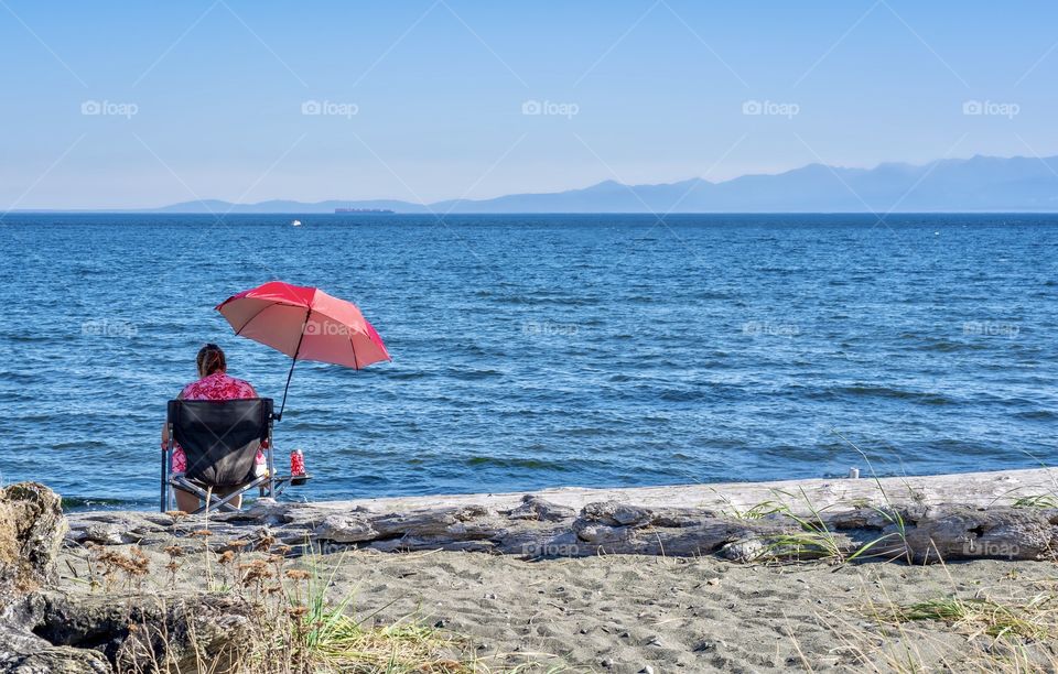 Woman wearing red with red beach umbrella and drink container 