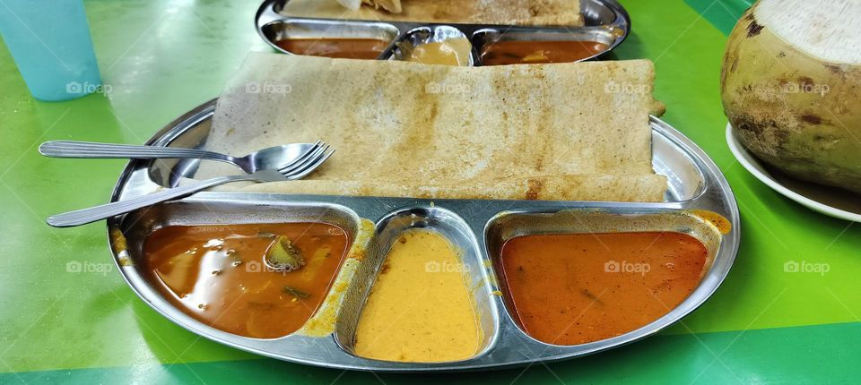 A plate of colourful Indian food dosa and curry close shot