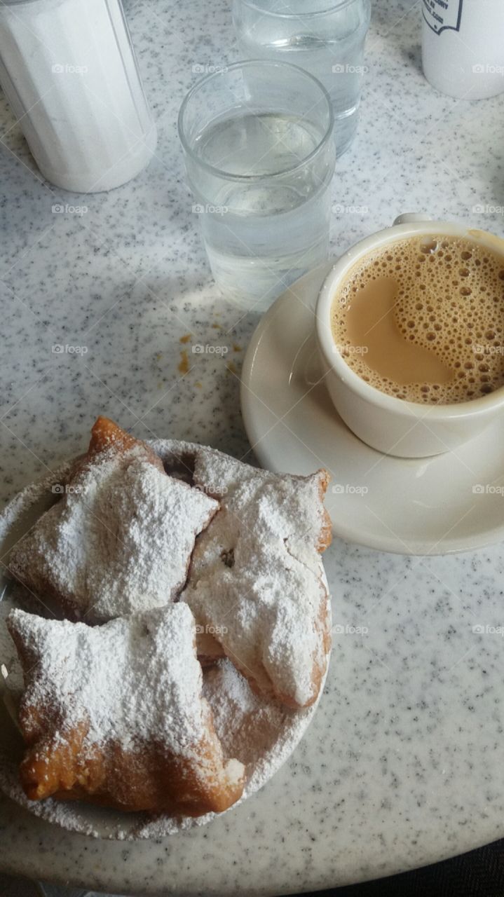 Cafe au lait with three freshly powdered beignets in New Orleans