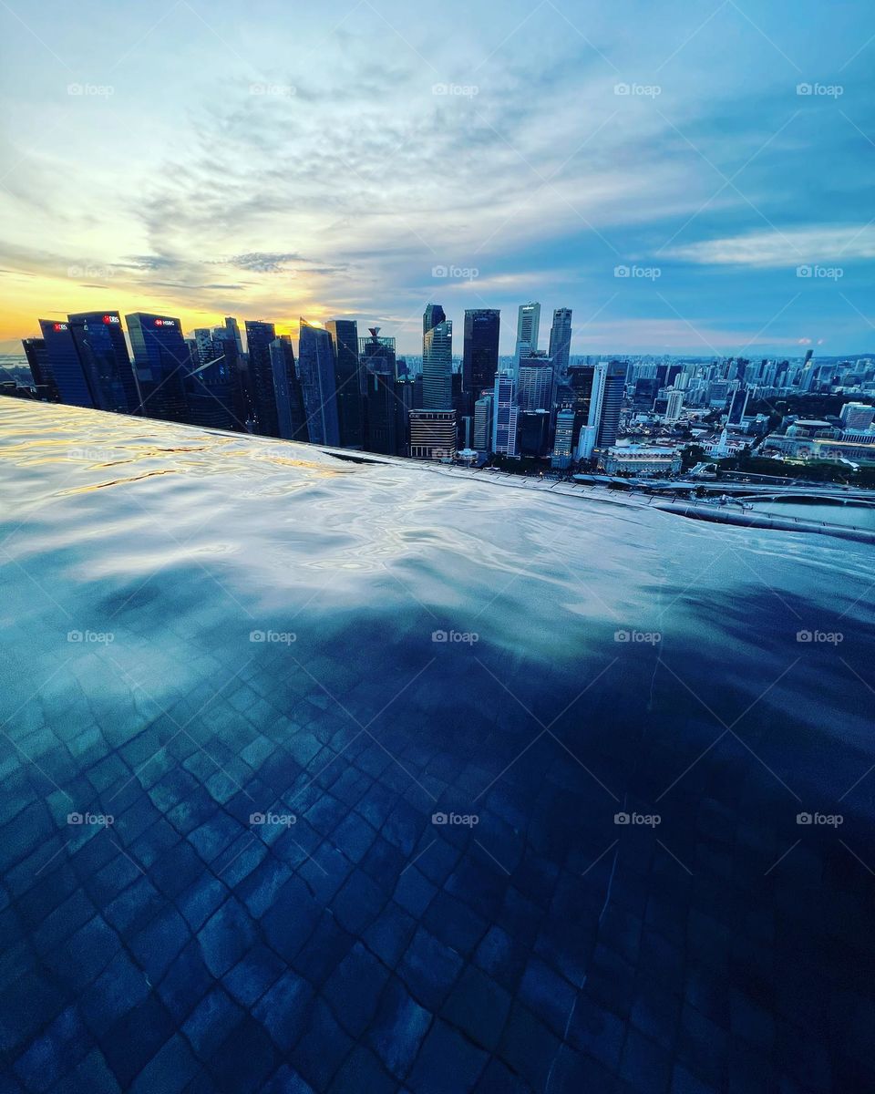 View from infinity pool onto the skyline of Singapore at sunset.