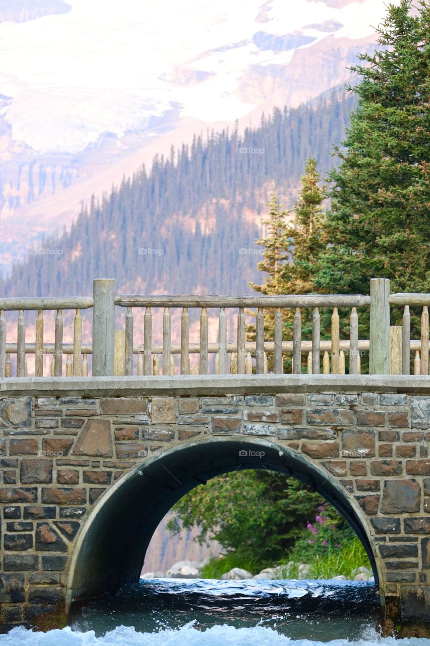 Scenic Romantic arched stone bridge crossing waterway into beautiful turquoise Lake Louise in Canada's Rocky Mountains 