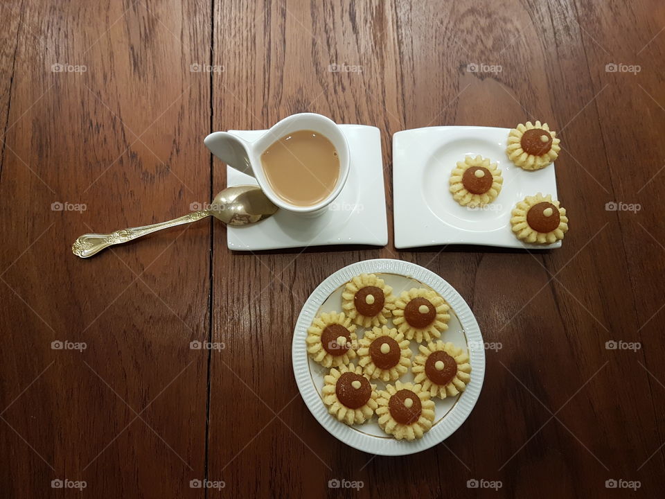 Tea time with delicious and pretty homemade pineapple tarts pastry in shapes of flower on white plate and tea