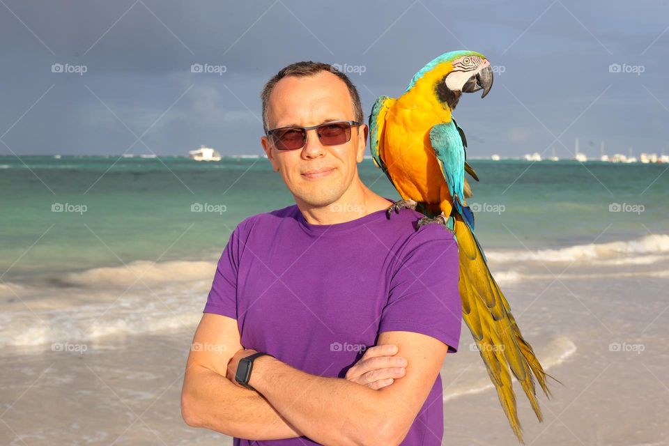 My nice man, my love, my dearest husband. Photo was taken in Dominican Republic. Colourful parrot and smiling nice man. Man portrait in a holiday. Summer time, travel time.