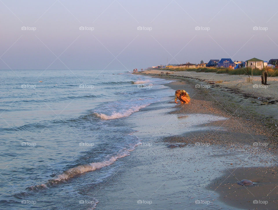 Girl collects seashells and pebbles on the seashore