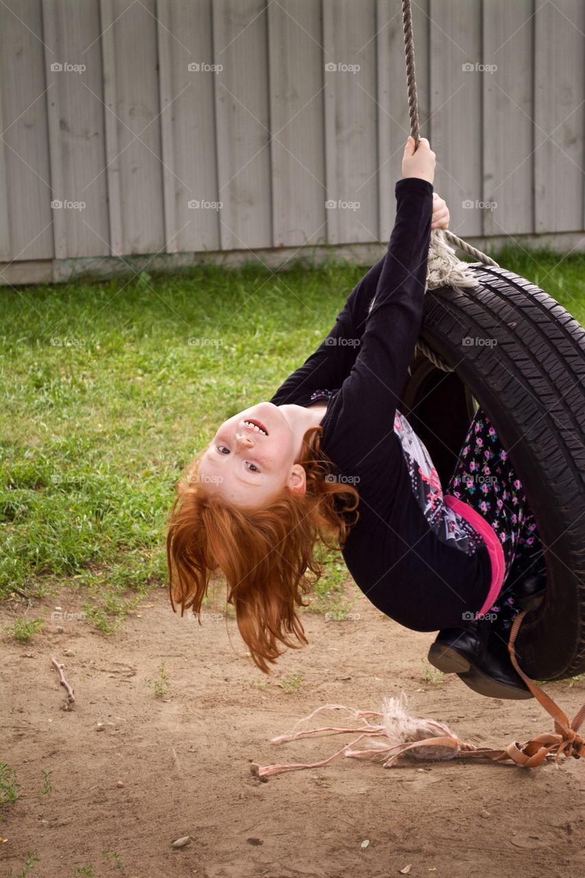 Smiling child swinging on a tire swing.