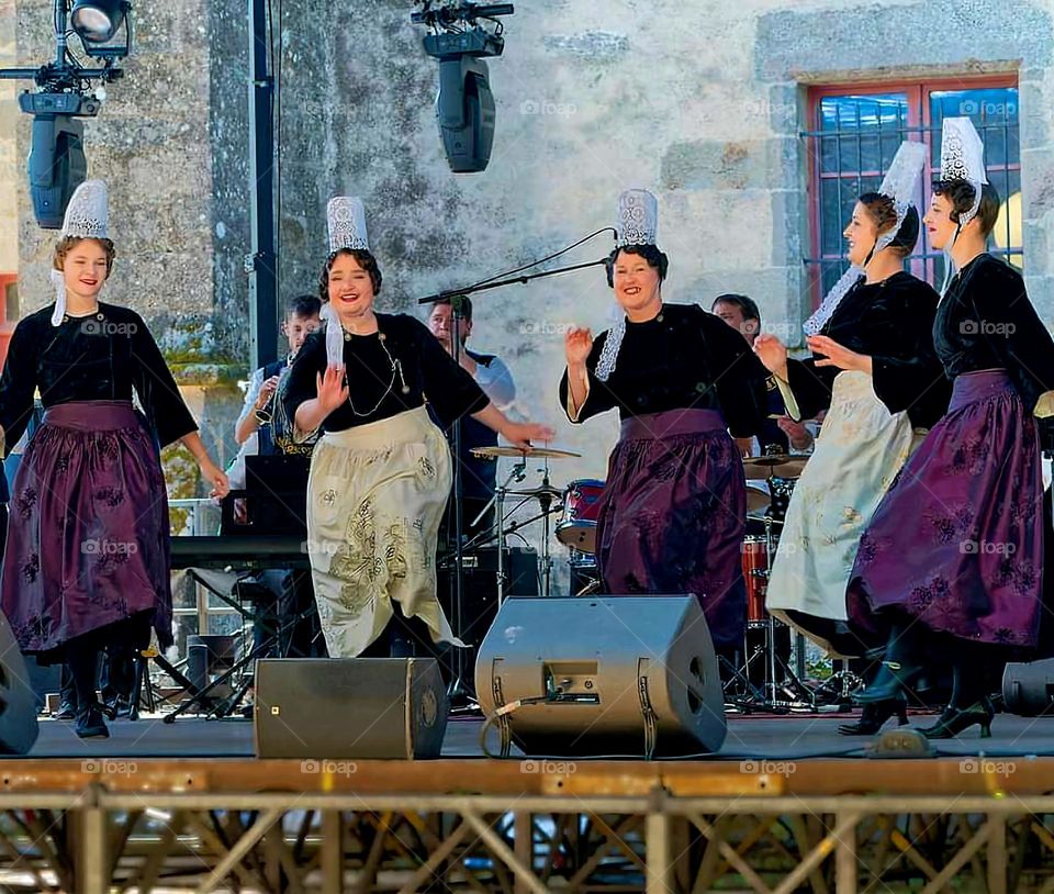 Women dressed in Breton traditional costumes dancing on stage at the Embroiderers Festival in Pont l'Abbé