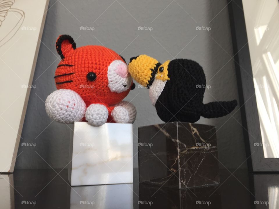 Toy tiger and toy bird from knitted wool on a stone socket at home 
