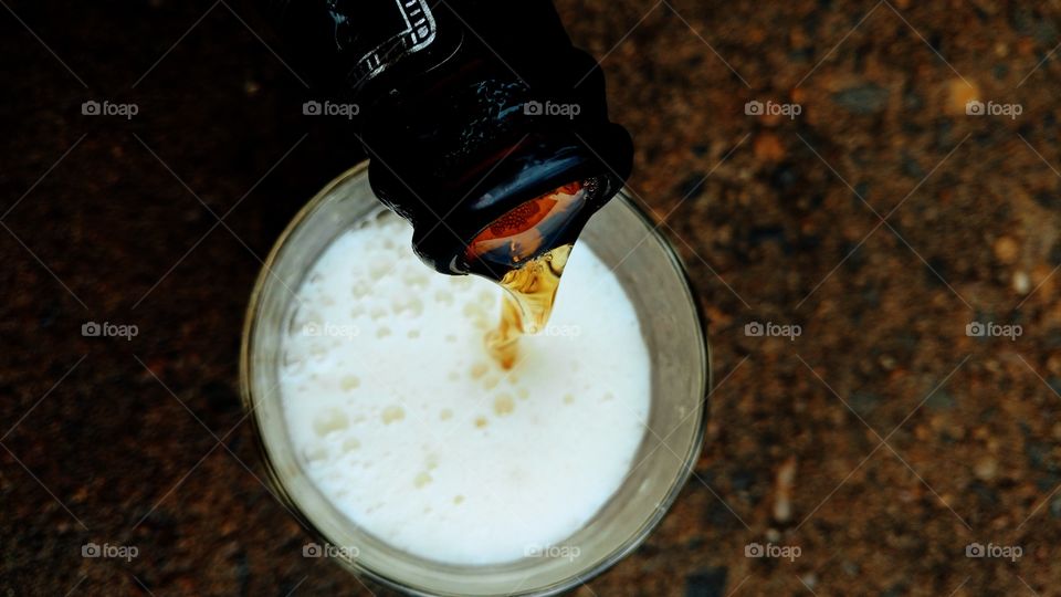Bebida alcoólica. Garrafa de cerveja enchendo um copo.