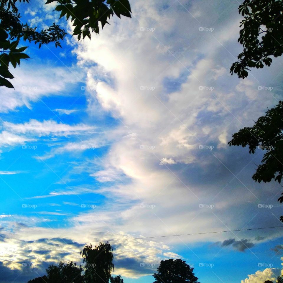Blue sky, white clouds, green trees.