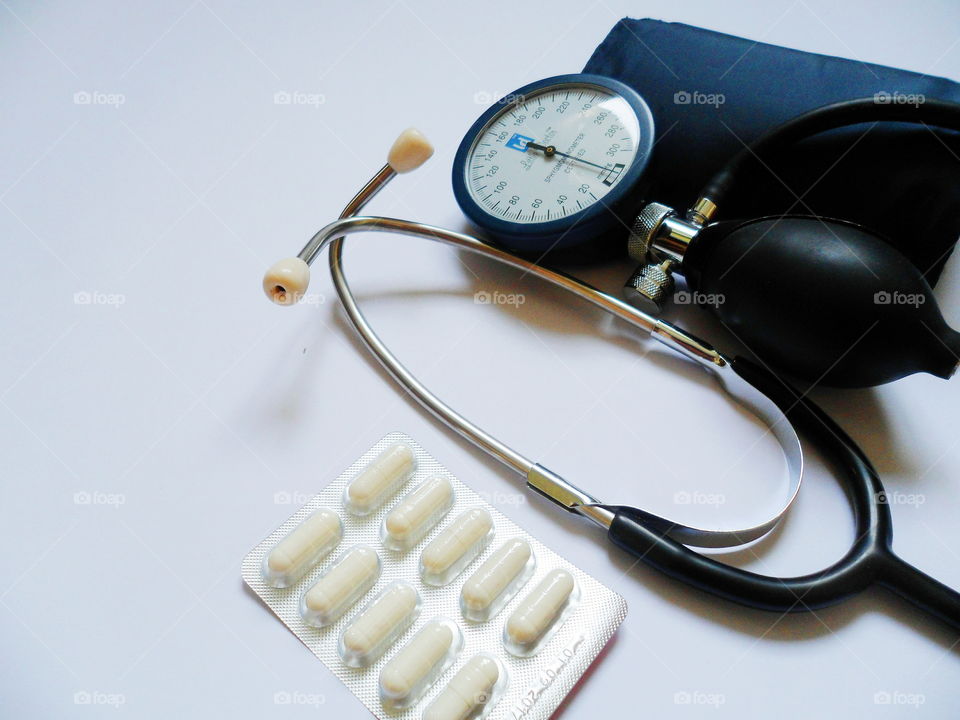 tonometer device for measuring blood pressure and pills on a white background